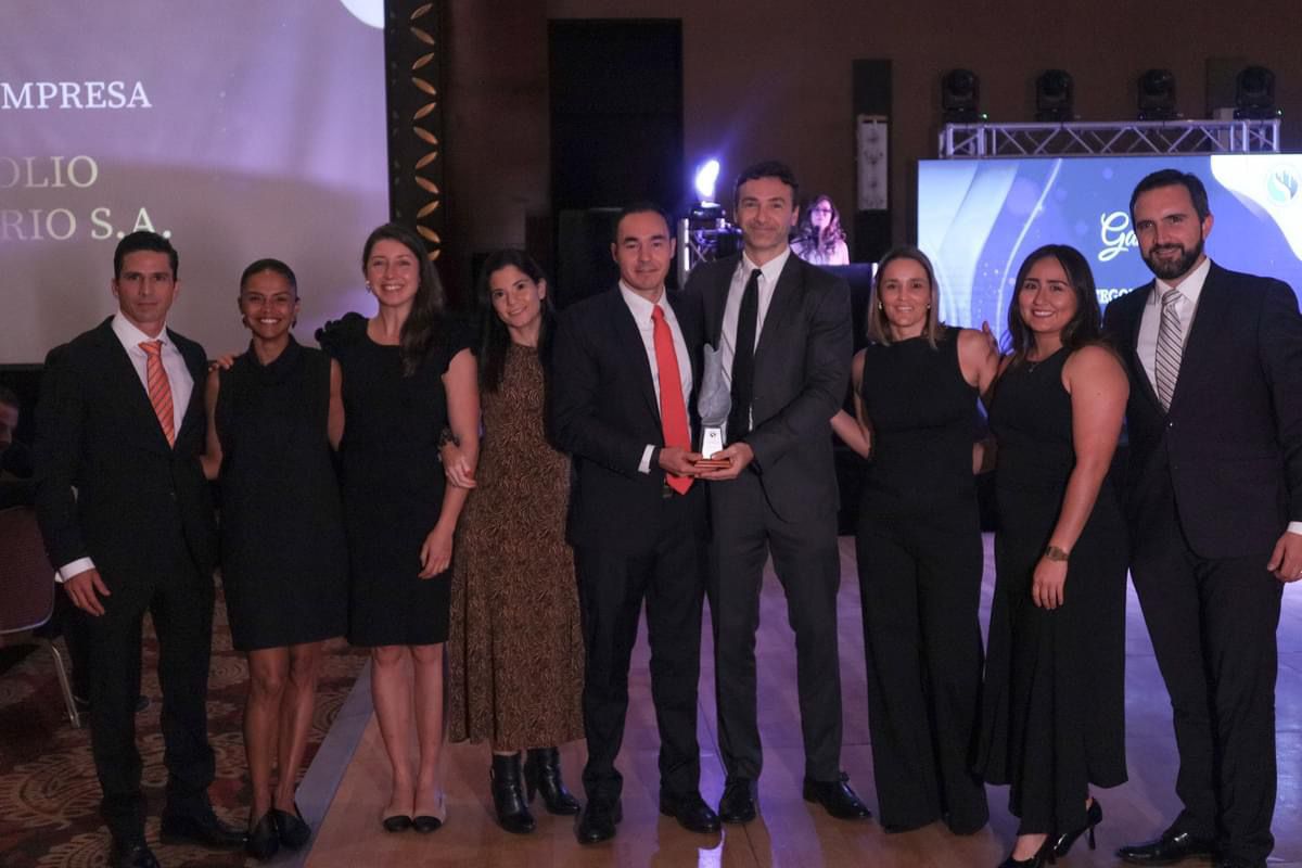 Equipo de Portafolio Inmobiliario posando en una ceremonia de premiación, donde reciben un reconocimiento. Los miembros del equipo están vestidos de manera formal y se muestran sonrientes y unidos, sosteniendo el trofeo que simboliza su logro