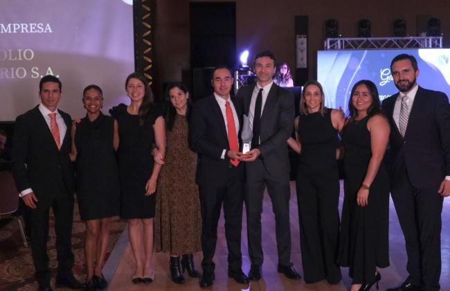 Equipo de Portafolio Inmobiliario posando en una ceremonia de premiación, donde reciben un reconocimiento. Los miembros del equipo están vestidos de manera formal y se muestran sonrientes y unidos, sosteniendo el trofeo que simboliza su logro